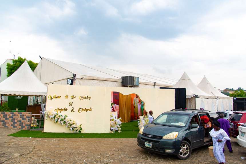 The marquee from outside on the day, with welcome signage, greenery and cars inside the gate.